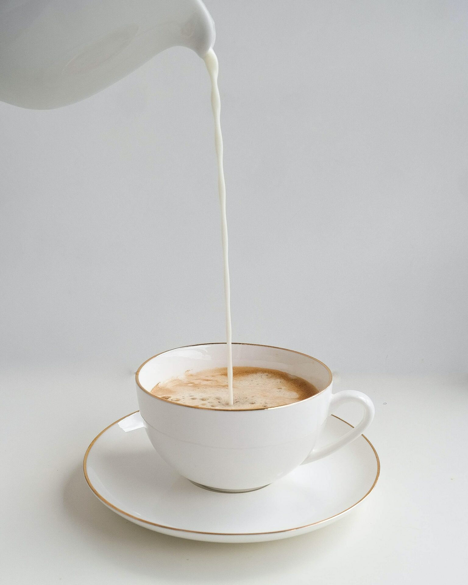 pouring milk into a coffee cup